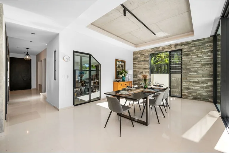 Dining area with stacked-stone feature wall and concrete ceiling, Hawkstone project